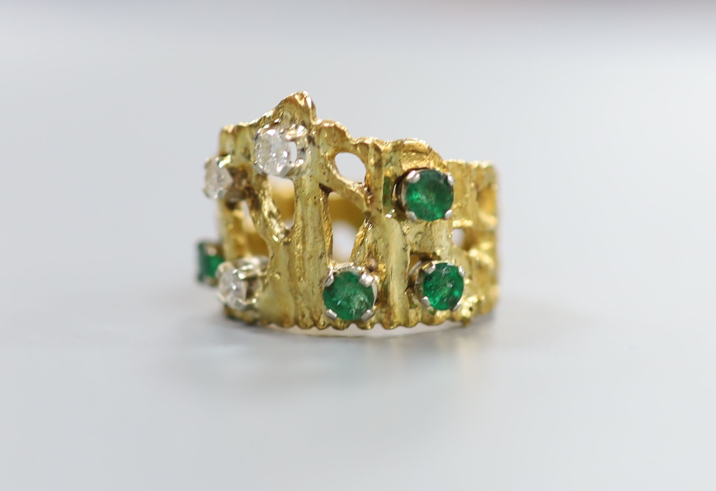 A pierced and textured 18ct, emerald and diamond set dress ring, size J, gross weight 8.3 grams.